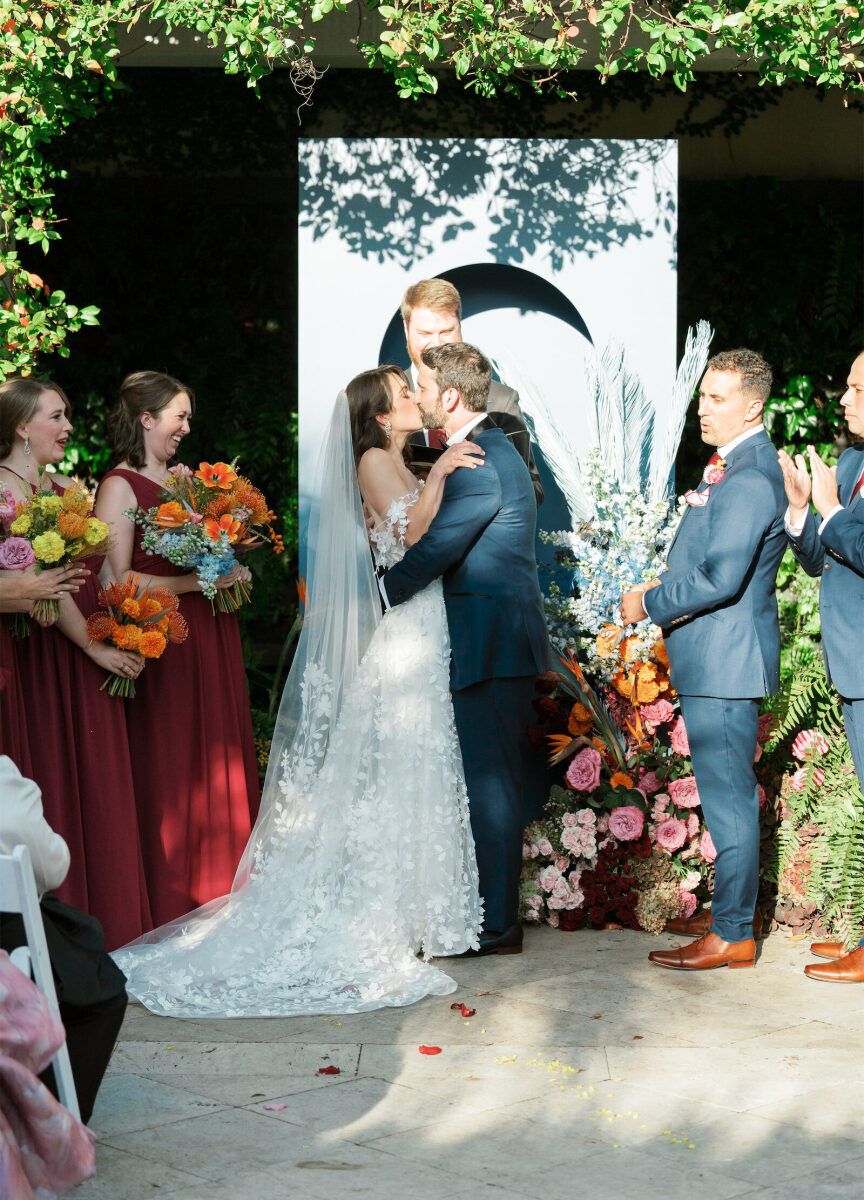 A bride and groom kiss at their art-inspired wedding ceremony, which incorporated a bold color palette.