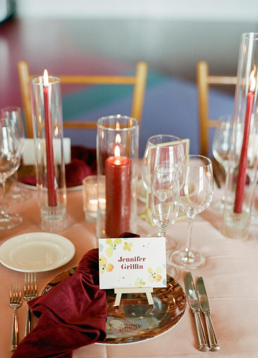 Tiny easels hold watercolor place cards at each place setting of this art-inspired wedding reception.