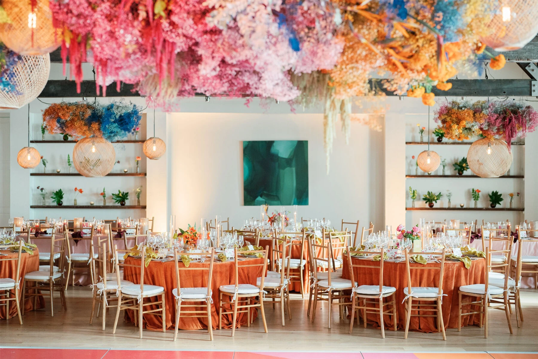 Colorful floral installations and woven light fixtures hung overhead at an art-inspired wedding at Cannon Green in Charleston, South Carolina.