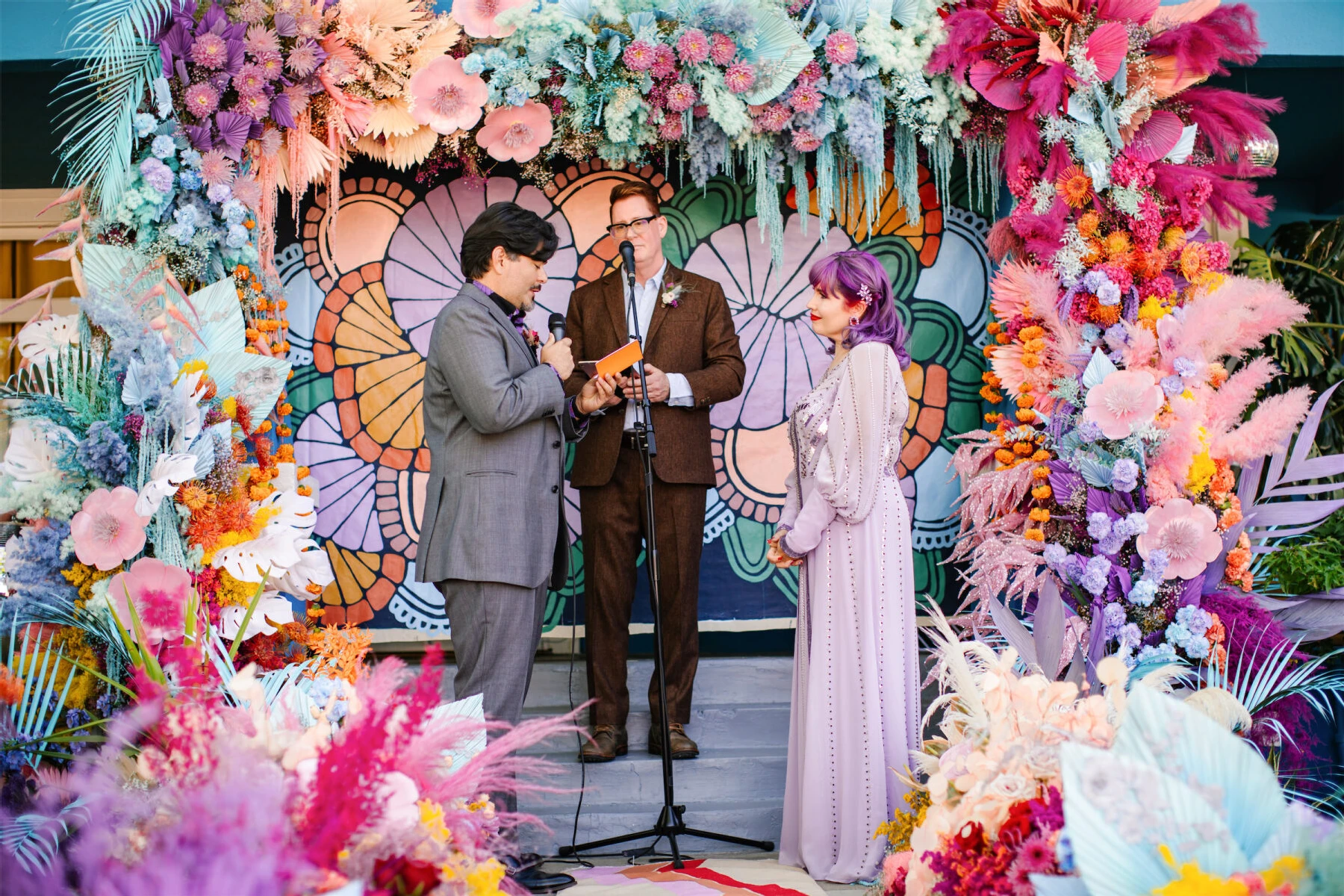A groom reads his vows to his soon-to-be-wife during their vibrant, outdoor wedding in California.